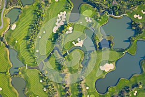 Aerial view of a golf course fairway and green with sand traps, trees and golfers