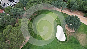 Aerial view of a golf course located in a city with lush trees surrounding the playing area