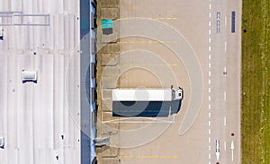 Aerial view of goods warehouse. Logistics center in industrial city zone from above. Aerial view of trucks loading at logistic