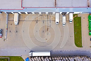 Aerial view of goods warehouse. Logistics center in industrial city zone from above. Aerial view of trucks loading at logistic