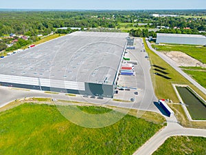 Aerial view of goods warehouse. Logistics center in industrial city zone from above. Aerial view of trucks loading at logistic