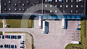 Aerial view of goods warehouse. Logistics center in industrial city zone from above. Aerial view of trucks loading at logistic cen