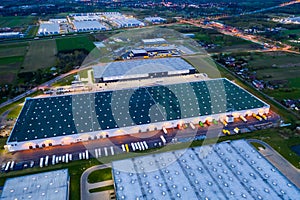 Aerial view of goods warehouse Night. Logistics center in industrial city zone from above. Aerial view of trucks loading at