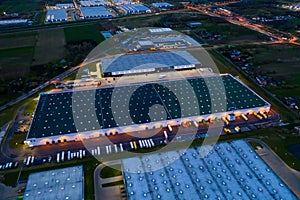 Aerial view of goods warehouse Night. Logistics center in industrial city zone from above. Aerial view of trucks loading at