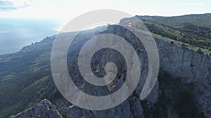 Aerial view of gorgeous white cliff and people standing with flags on the top against blue sky and sea in bright summer