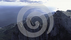 Aerial view of gorgeous white cliff and people standing with flags on the top against blue sky and sea in bright summer