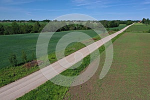 Aerial view of gravel road on farmland fields in spring