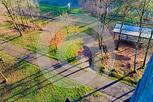 Aerial view of green area of old train station, woman standing with her dog on trail