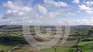 Aerial view of green farmland in Ireland. Irish rural landscape, panorama, little village, empty road, hills in the