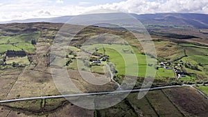 Aerial view of green farmland in Ireland. Irish rural landscape, panorama, little village, empty road, hills in the