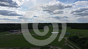 Aerial view of green fields, horse stable and forest in the countryside