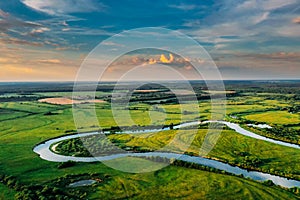 Aerial View Of Green Forest, Meadow And River Landscape In Sunny Evening. Top View Of European Nature From High Attitude