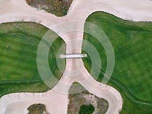 Aerial view of the green grass of the golf course. Bridge between hills