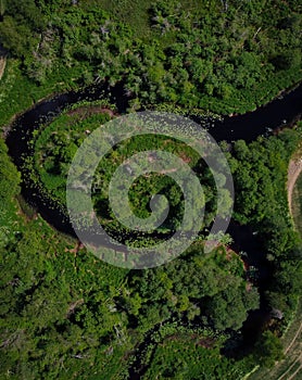 Aerial view of green meadow fields with zigzag channel water