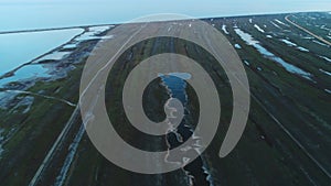 Aerial view of green piece of land with roads and swamps near the river or lake in the early spring. Shot. Picturesque