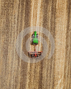 Aerial view of green tractor working in the field.