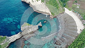 Aerial view of the green tropical coast of the island of Nusa Penida, Atuh beach, Bali, Indonesia.Clear blue ocean waves