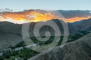 Aerial view of green valley in between high deserted mountains during sunset