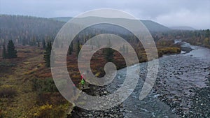 Aerial view of group of people walking along fast flowing river. Clip. Hikers walking through the mossy path leading to