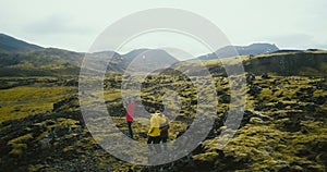 Aerial view of group of tourists hiking on lava fields in Iceland. Woman photographer holding camera, waiting friends