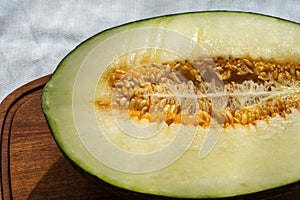 Aerial view of half green melon with orange seeds, on wooden table and white tablecloth