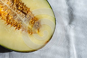 Aerial view of half green melon with seeds, on white tablecloth