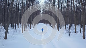 Aerial view on happy girl who runs around the snowdrifts in the forest. Scenic winter landscape