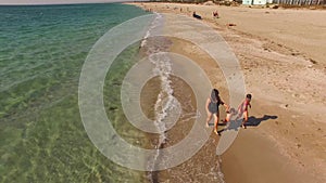 AERIAL VIEW. Happy Mother With Two Children Running On The Beach