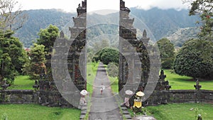 Aerial view of happy tourist woman with drone running through bali traditional gate in bedugul Traditional Balinese
