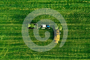 Aerial view of harvest field with tractor moving hay bale