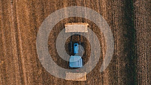 Aerial view of harvest field with tractor moving hay bale around