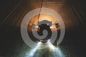 Aerial view of harvester harvesting wheat at night