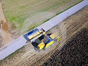 Aerial view of harvester unloads the corn into the trailer