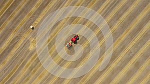 Aerial view of haymaking processed into round bales. Red tractor works in the field