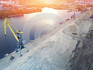 Aerial view of heavy crane loading bulk goods at Dnieper river cargo port terminal in Kiev at  evening sunset time. Industrial