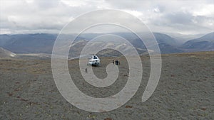 Aerial view of a helicopter and a group of hikers on a mountain top. Clip. Concept of adventure and tourism, people