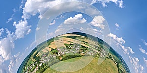 Aerial view from high altitude of little planet earth with small village houses and distant green cultivated