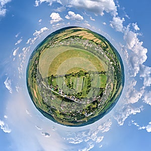 Aerial view from high altitude of little planet earth with small village houses and distant green cultivated