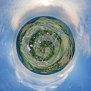 Aerial view from high altitude of little planet earth with small village houses and distant green cultivated