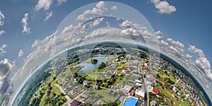 Aerial view from high altitude tiny planet in sky with clouds overlooking old town, urban development, buildings and crossroads.