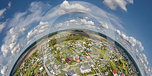 Aerial view from high altitude tiny planet in sky with clouds overlooking old town, urban development, buildings and crossroads.