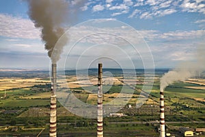 Aerial view of high chimney pipes with grey smoke from coal power plant. Production of electricity with fossil fuel