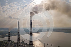 Aerial view of high chimney pipes with grey smoke from coal power plant. Production of electricity with fossil fuel