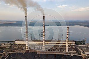 Aerial view of high chimney pipes with grey smoke from coal power plant. Production of electricity with fossil fuel