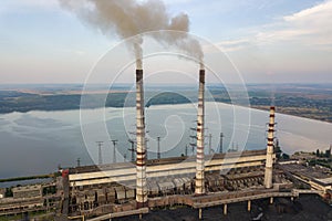 Aerial view of high chimney pipes with grey smoke from coal power plant. Production of electricity with fossil fuel