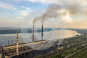 Aerial view of high chimney pipes with grey smoke from coal power plant. Production of electricity with fossil fuel