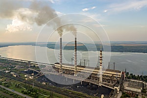 Aerial view of high chimney pipes with grey smoke from coal power plant. Production of electricity with fossil fuel