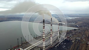 Aerial view of high chimney pipes with grey smoke from coal power plant. Production of electricity with fossil fuel.