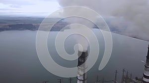 Aerial view of high chimney pipes with grey smoke from coal power plant. Production of electricity with fossil fuel.