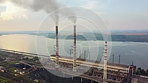 Aerial view of high chimney pipes with grey smoke from coal power plant. Production of electricity with fossil fuel.